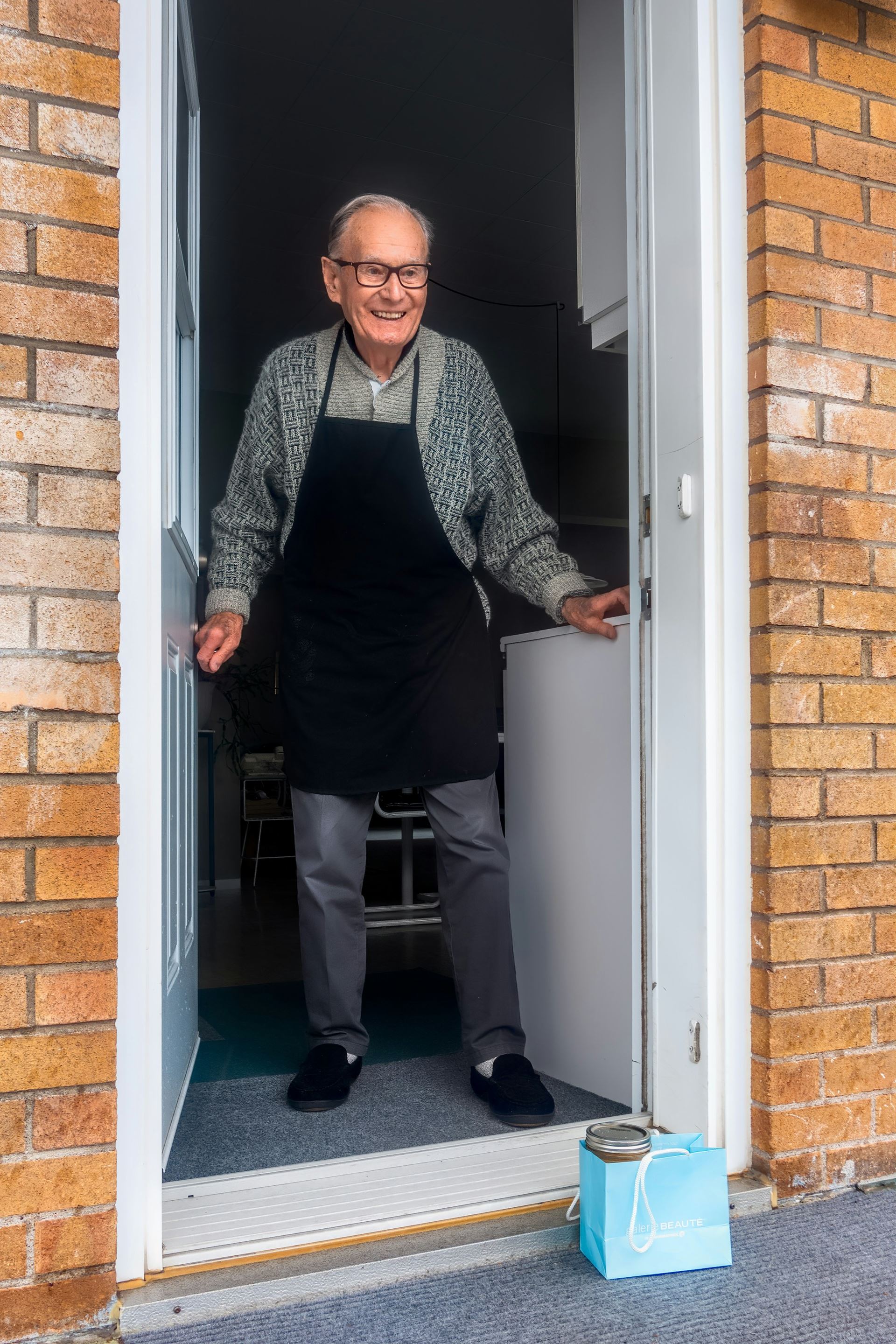 an older man stepping outside his front door