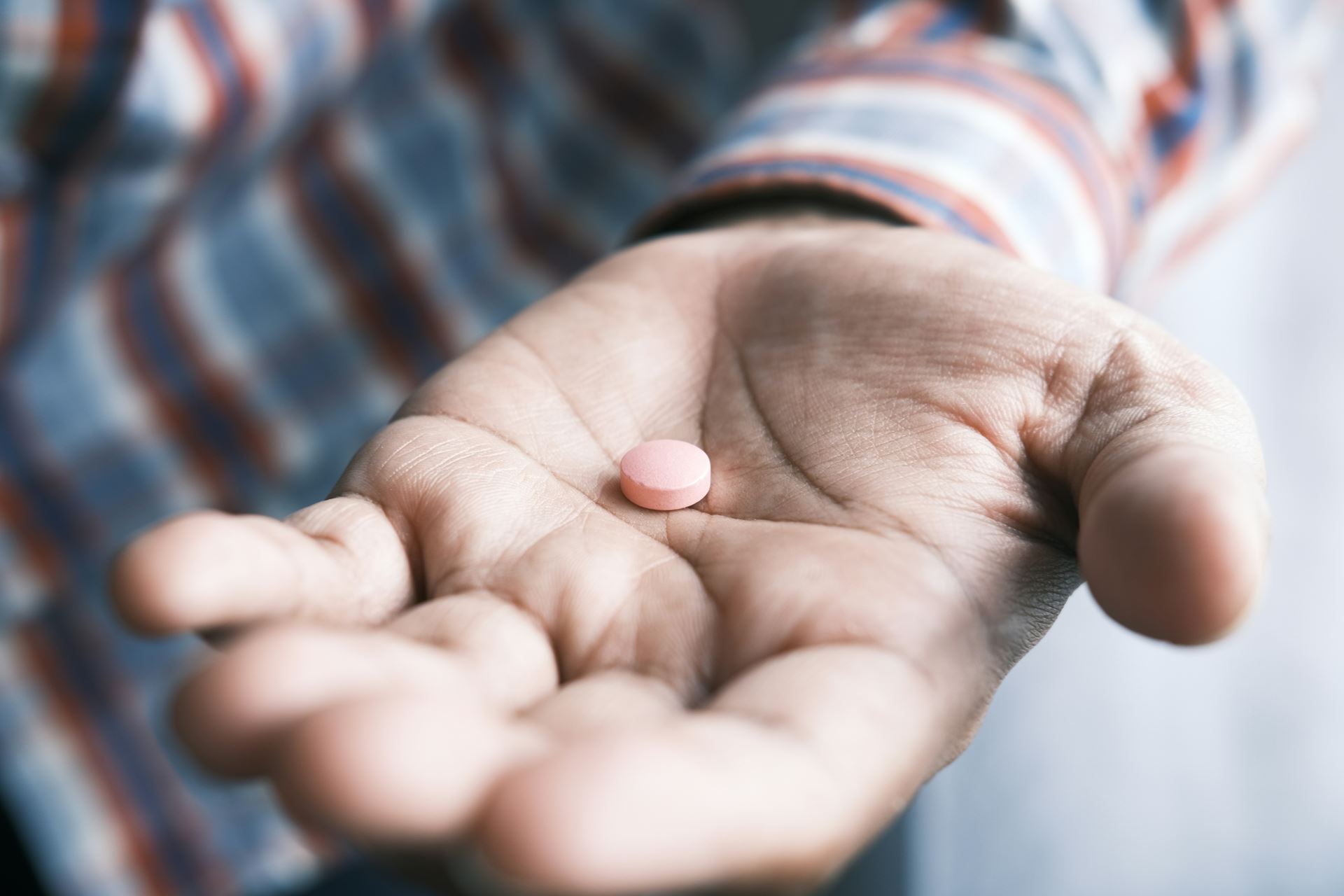 a mans holding a single medical tablet