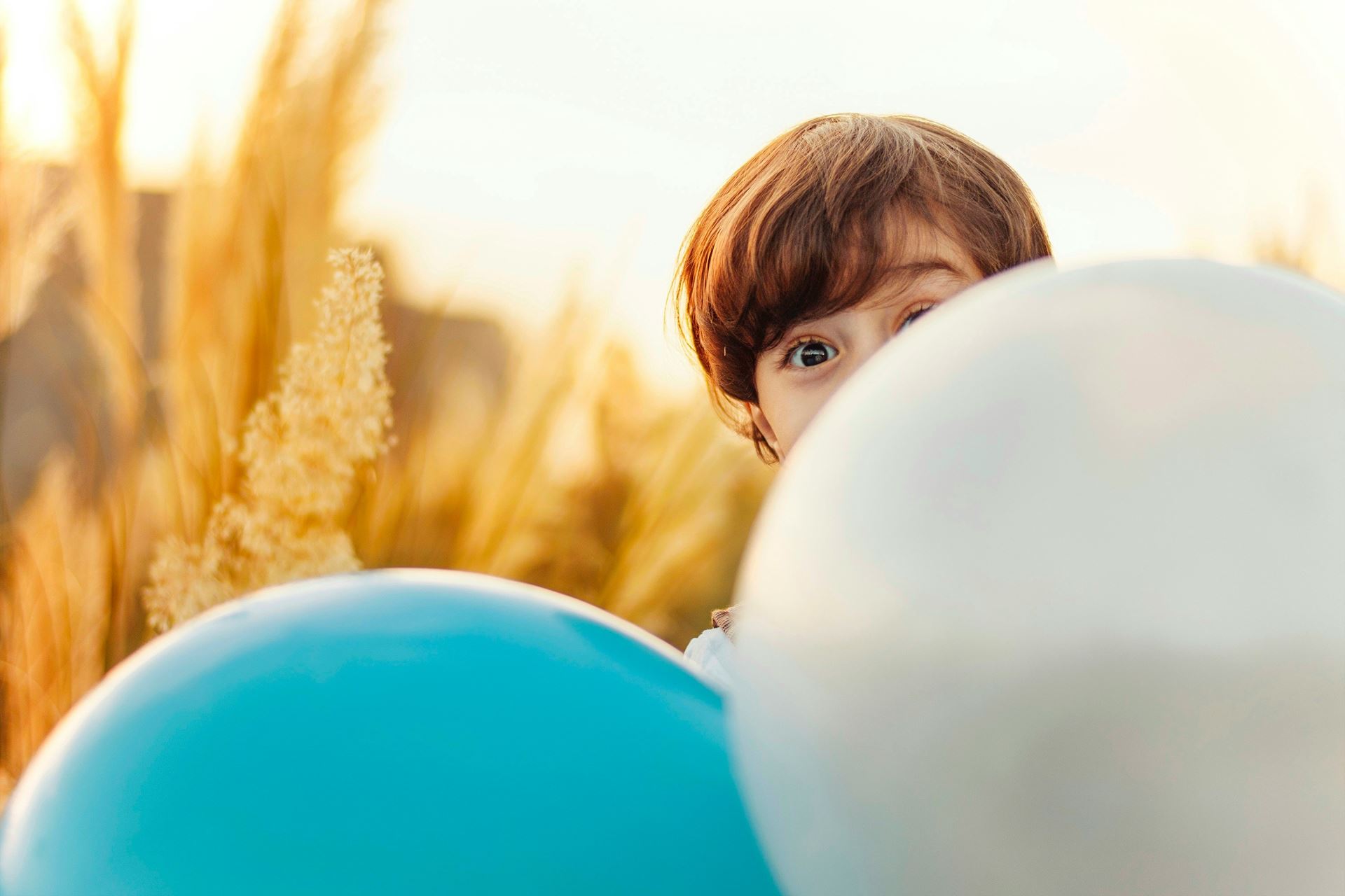 a child peeking out from behind a balloon