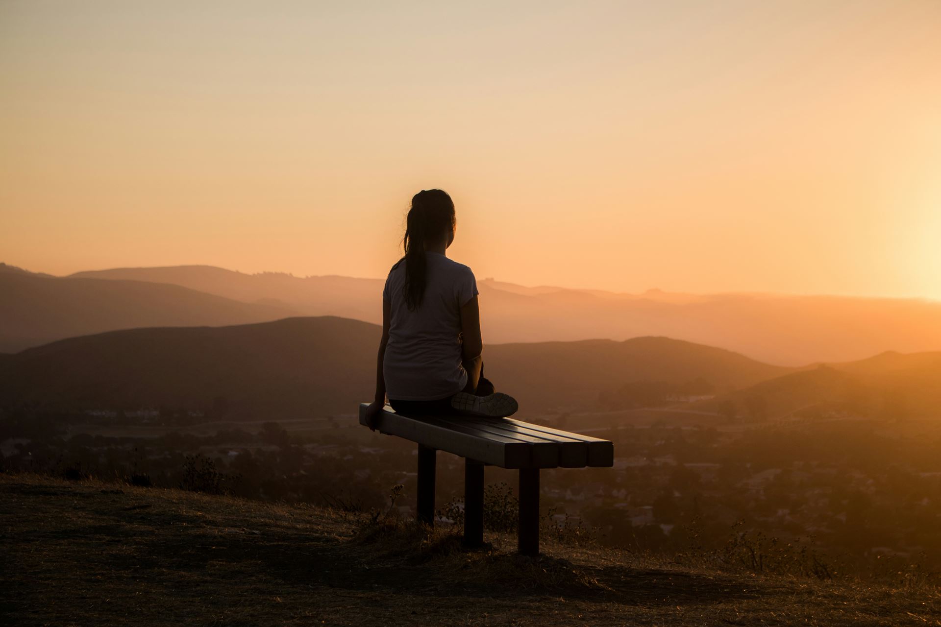 a silhouette of a woman looking at a sunset